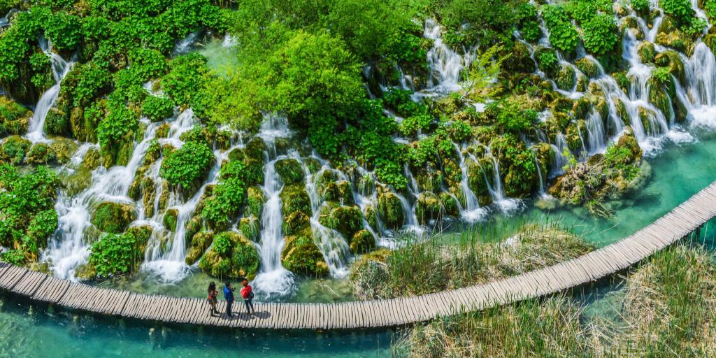 People on a wooden walkway looking at the waterfalls in Plitvice Jezera, Croatia