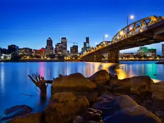 Portland, Oregon, USA with the city skyline in the distance and Willamette River in the foreground taken at night.