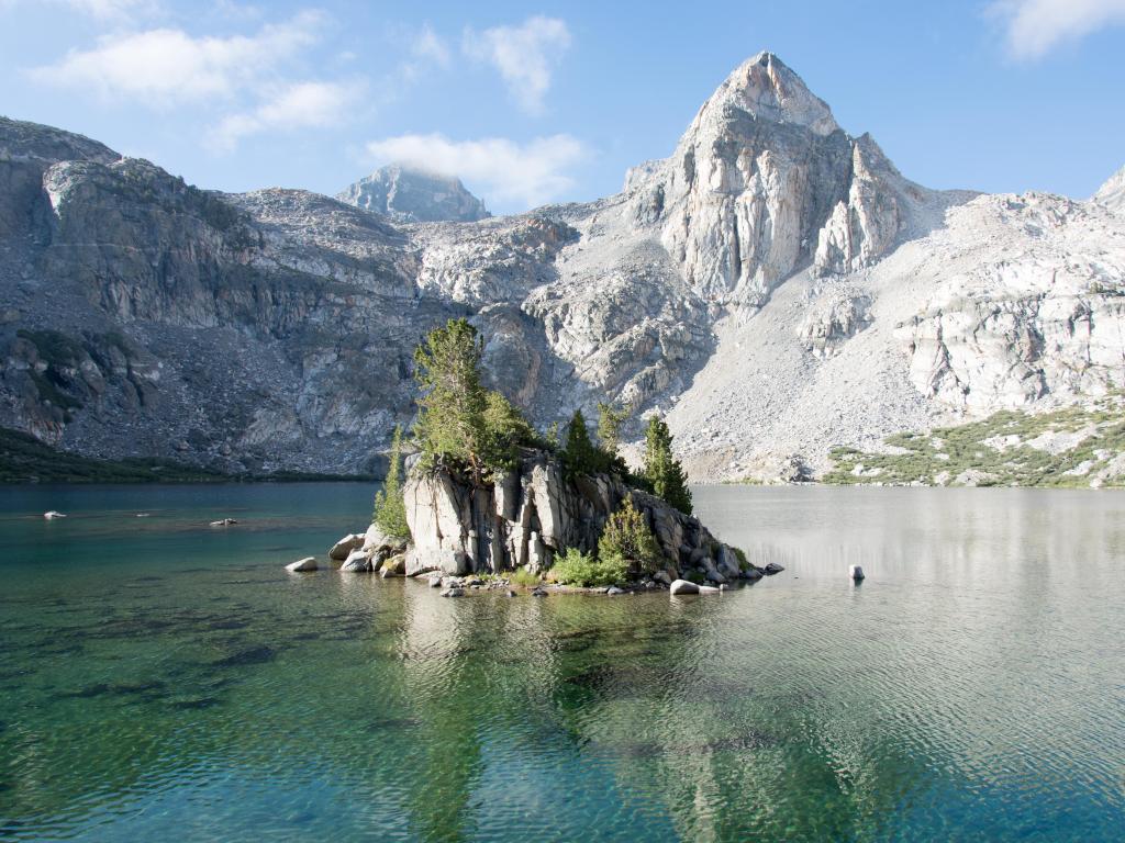 King's Canyon National Park, California, USA taken at the Painted Lady at Rae Lakes on a sunny day with clear water in the foreground and white cliffs in the background.