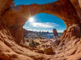 Double Arch in Moab, Utah, USA with snow and a sun star in a blue sky.