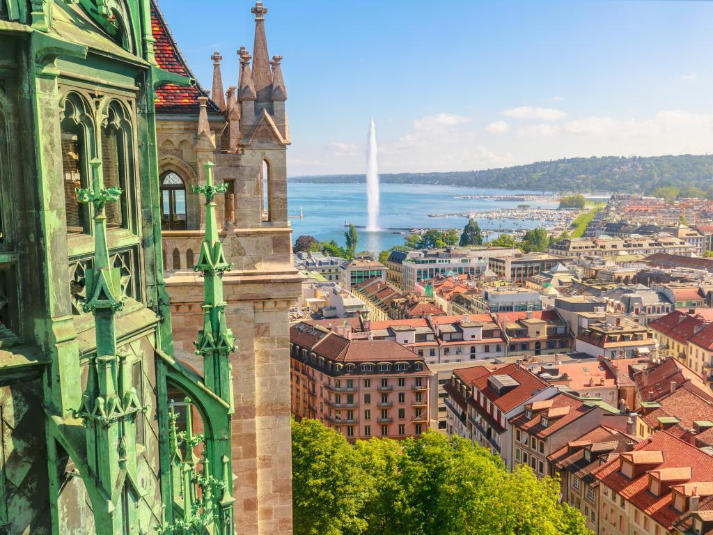 Geneva skyline, Leman Lake, Jet d'eau fountain, bay, harbor and Tower of Cathedral, French Swiss in Switzerland. View of Romanesque bell tower and spire of Saint-Pierre Cathedral. Sunny day blue sky.