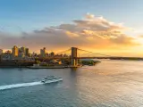 A ferry crossing the river towards Brooklyn Bridge at sunset