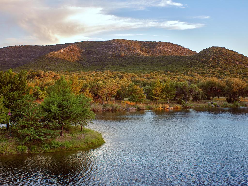A lake in Del Rio, Texas, USA with hills and trees in the distance.