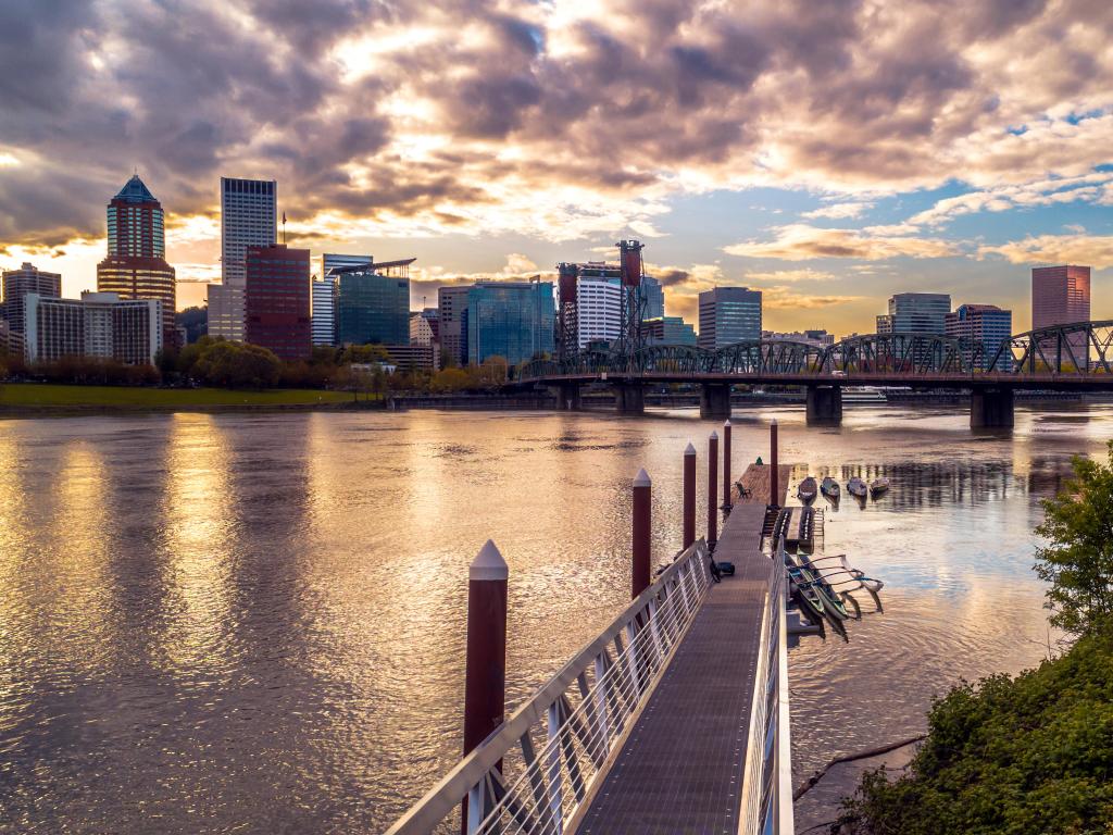 Portland, Oregon, USA with the cityscape at sunset and the river and bridge in the foreground.