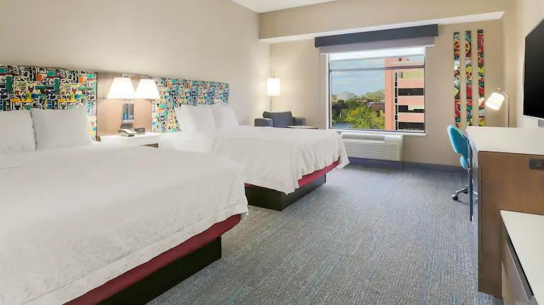Large family room, with white bedding and bright artwork and headboard at Hampton Inn & Suites Pittsburgh Downtown