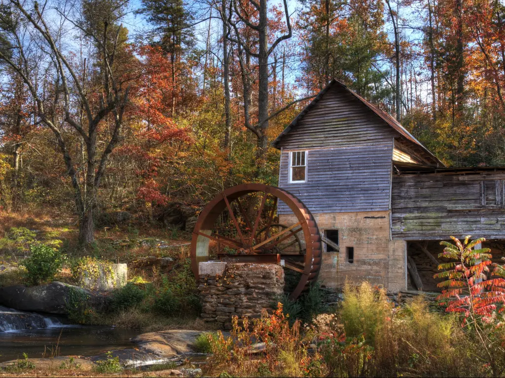 An old wooden grist mill in the forest in Georgia, USA, with fall leaves turning red and orange