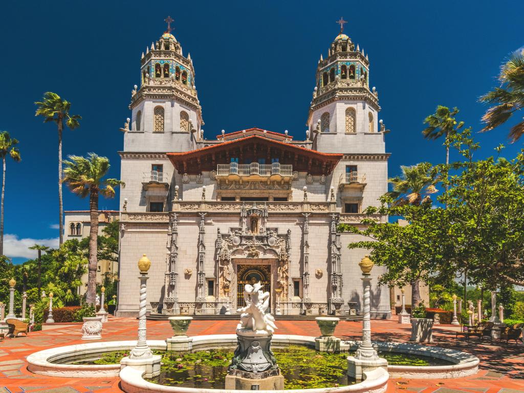 Exterior view of the extravagant Hearst Castle with a fountain in the front, taken on a sunny day