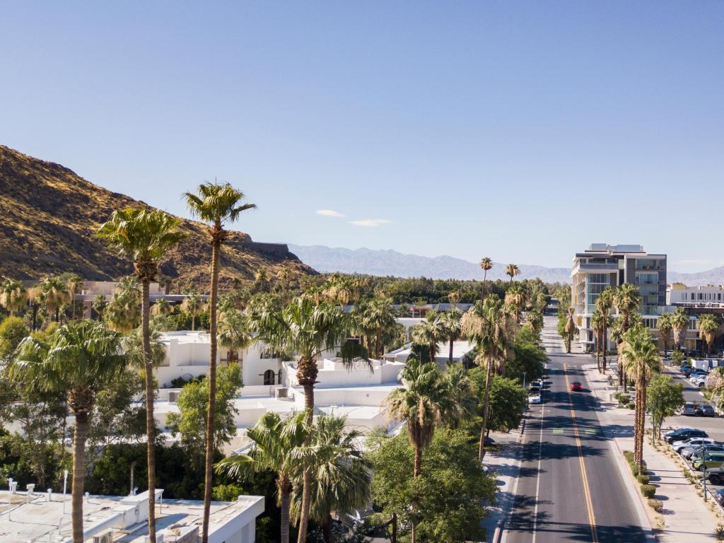 Palm Springs aerial view of downtown with palm trees lining the streets and distant mountains in the background.