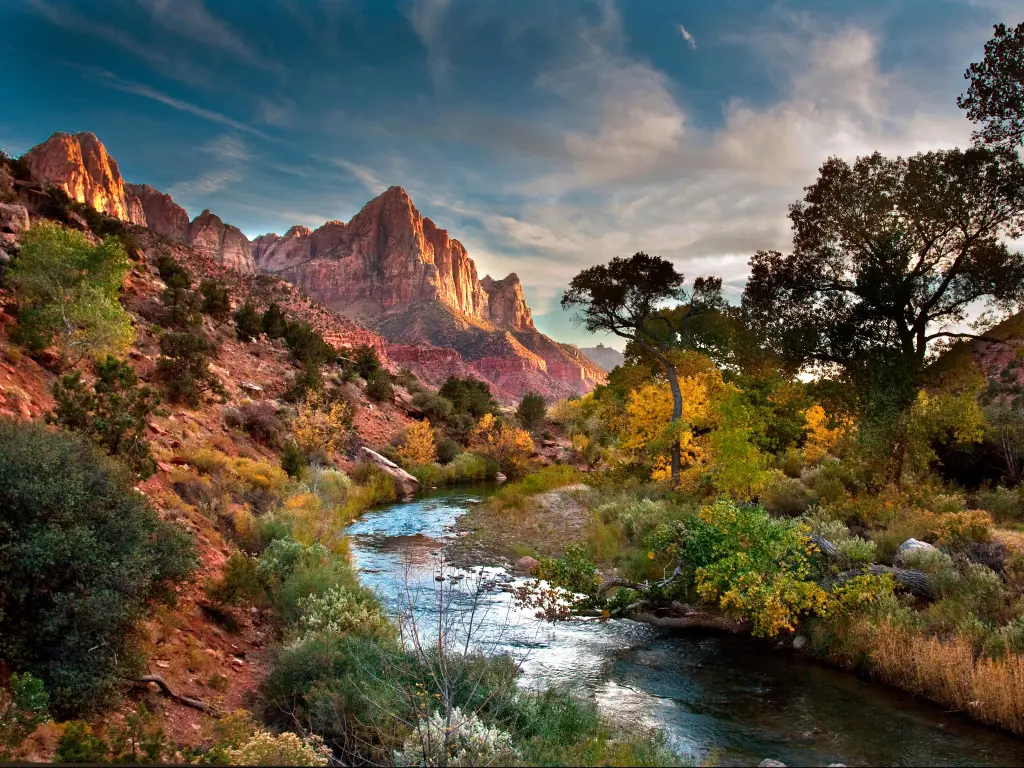 Zion National Park, Utah, USA with a stream and mountains in the distance at sunset.