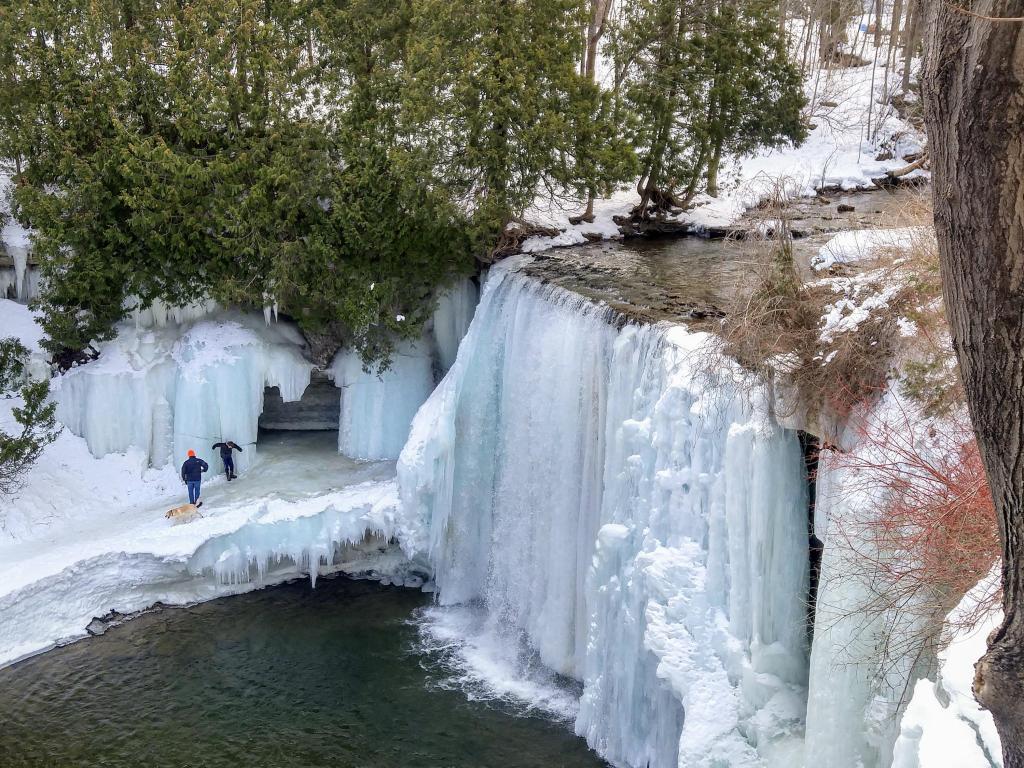 Frozen icy waterfalls and open water with people in the background