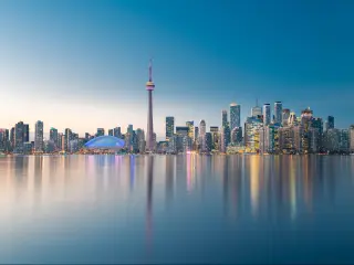 Toronto city skyline, Ontario, Canada taken at early evening with the skyscrapers lit up and reflected in the water in the foreground. 
