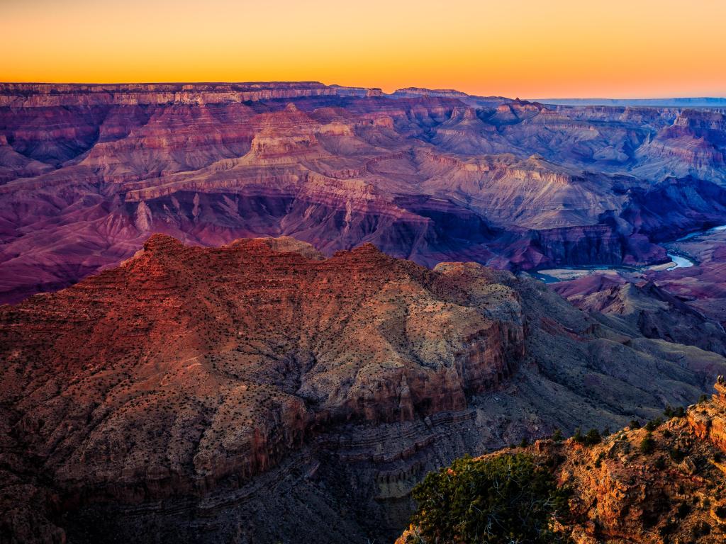 Grand Canyon National Park, Arizona taken at twilight looking at the valleys below with a yellow sky.