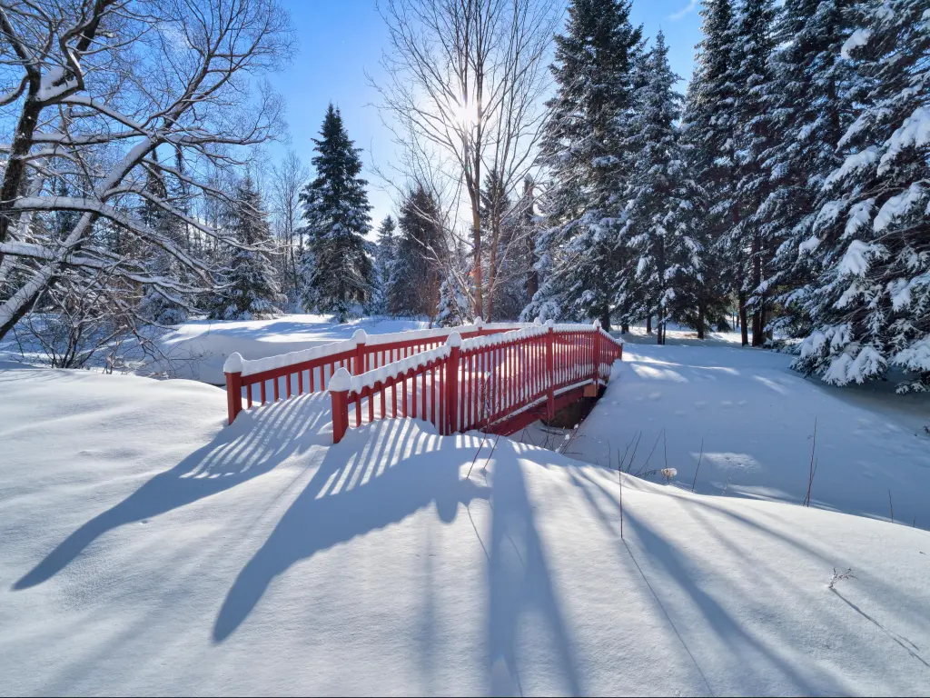 Quebec winters in the Laurentians. A red bridge is in focus, surrounded by fluffy snow.