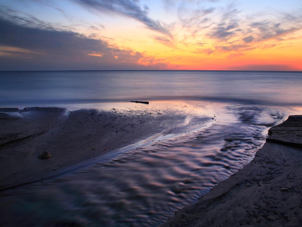 Lake Erie, New York, USA with a blazing sunset over the lake at the mouth of Crooked Creek, Dunkirk.