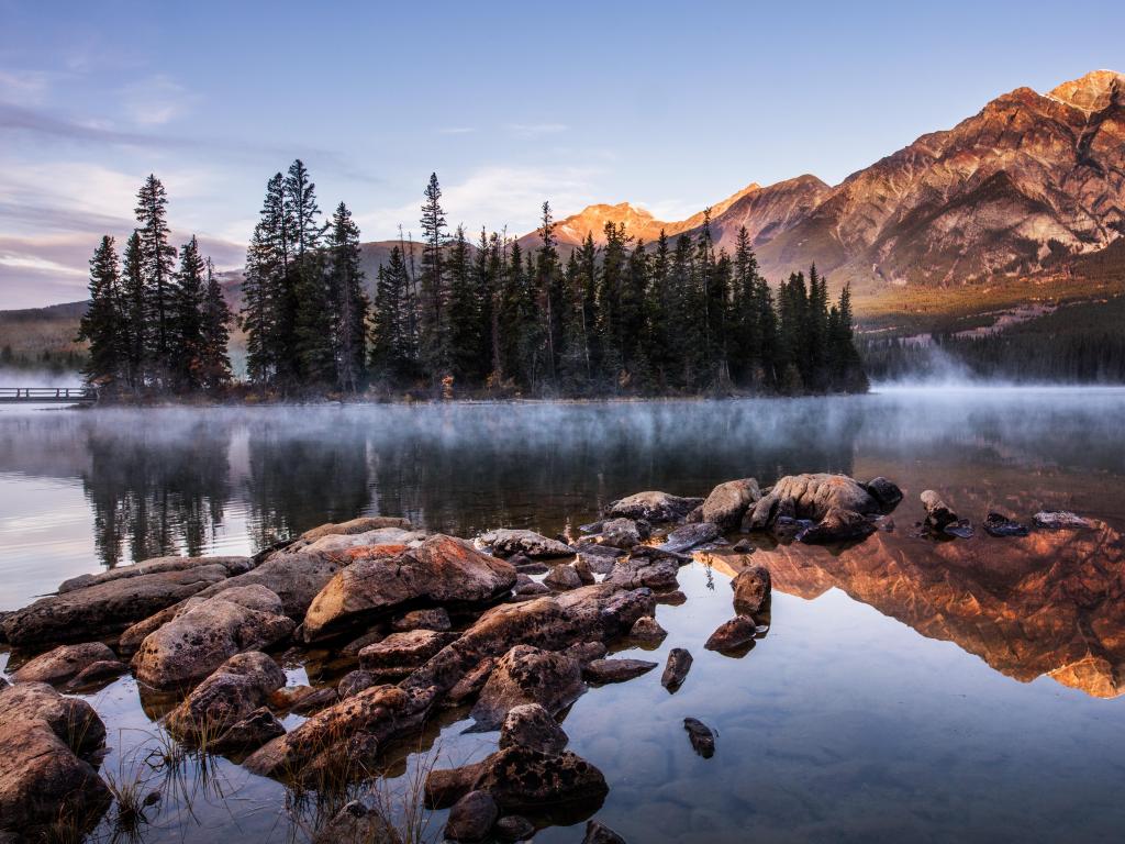 Pyramid Lake, Nevada, USA with rocks and trees, mist on the lake and mountains in the distance. 