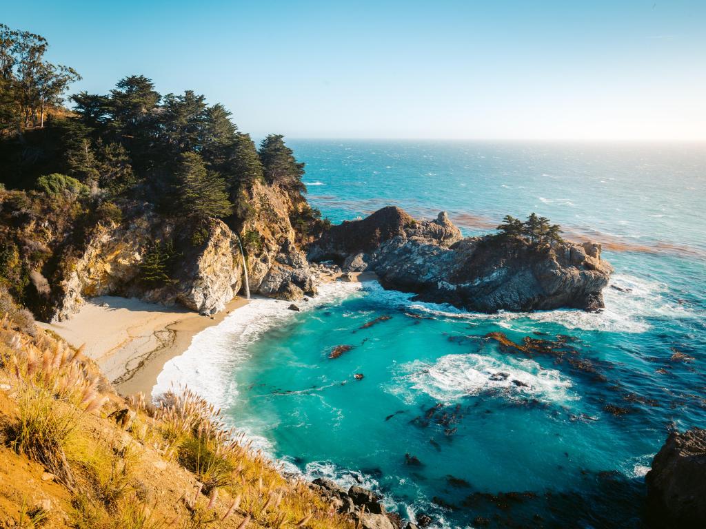 Beautiful view of the scenic McWay Falls in evening light at sunset on a beautiful sunny day from top of a hill in Julia Pfeiffer Burns State Park, Big Sur, California