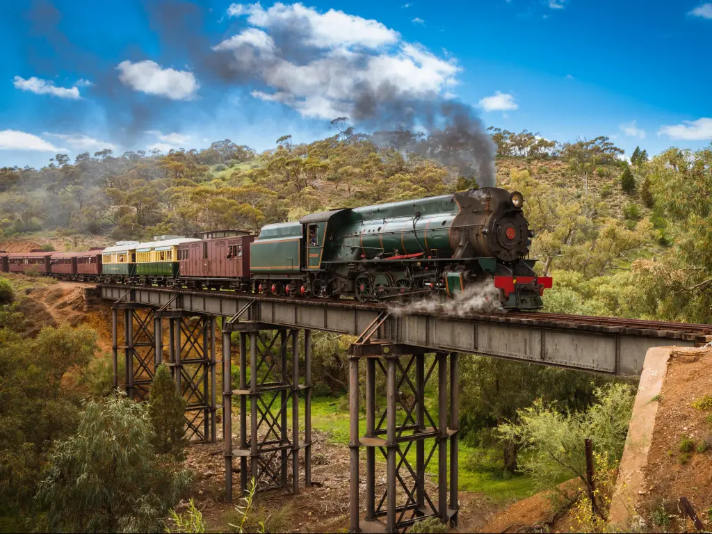 Pichi Richi tourist steam train, Australia ride in Flinders Ranges over a metal bridge with trees in the distance and on a sunny day.