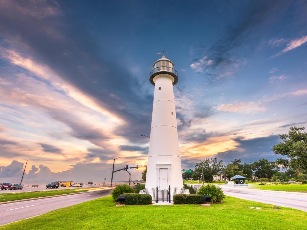 Biloxi, Mississippi USA with Biloxi Lighthouse at dusk in the centre, grass in the foreground and a dramatic sky above.