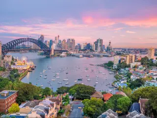 Downtown Sydney skyline at sunset with Harbour Bridge and a purple-hued sky