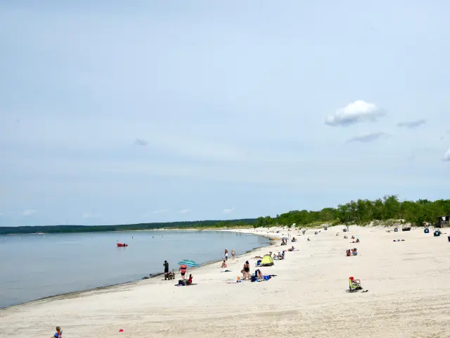 People on golden sandy beach by the lake on a sunny day