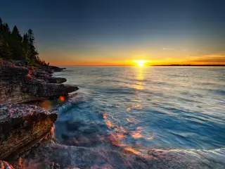 A beautiful sunset over the waves, photo taken from on top of rugged cliff