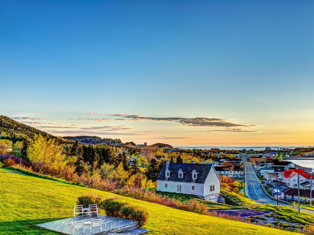 Perce, Gaspe Peninsula, Quebec, Canada with chairs on hill in the foreground taken during sunrise in Perce, and the cityscape in the background.