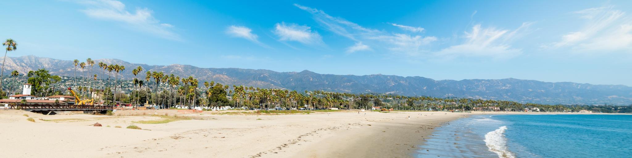 White sand in Santa Barbara shoreline, California with mountains in the background.
