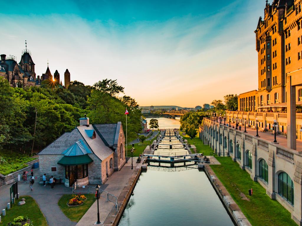 Rideau Canal Locks, Ottawa, Canada taken in summer with the canal in the foreground and tall buildings either side of the river and taken at sunset.