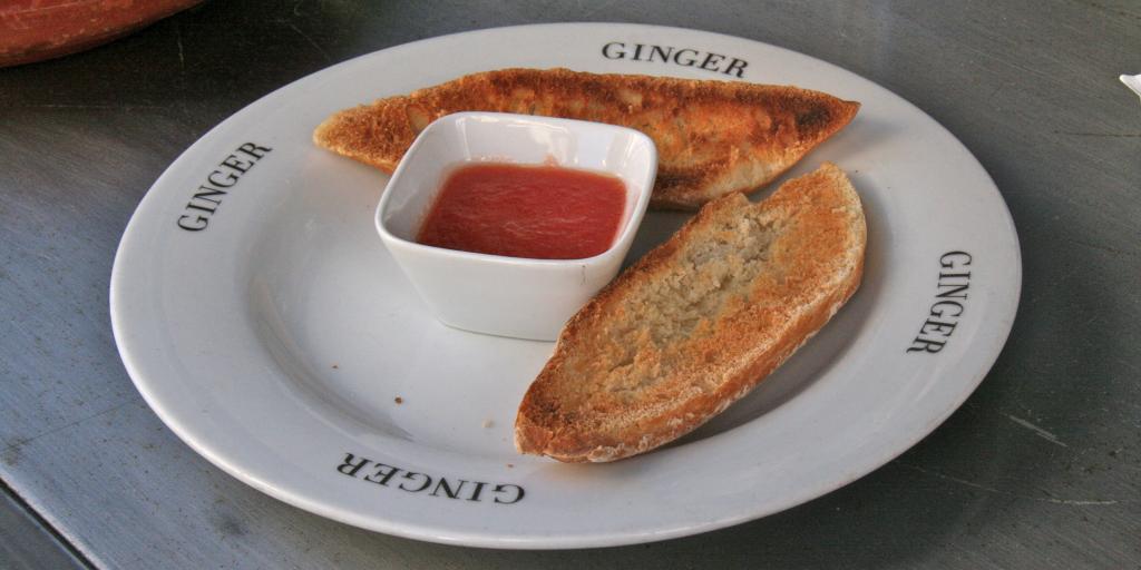 Two slices of toast on a plate with crushed tomatoes in the middle