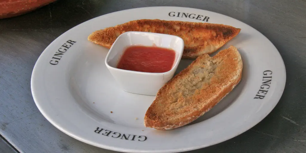 Two slices of toast on a plate with crushed tomatoes in the middle