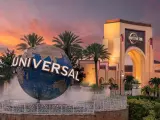 Universal Orlando's logo on the globe with the main gate in the background during sunset