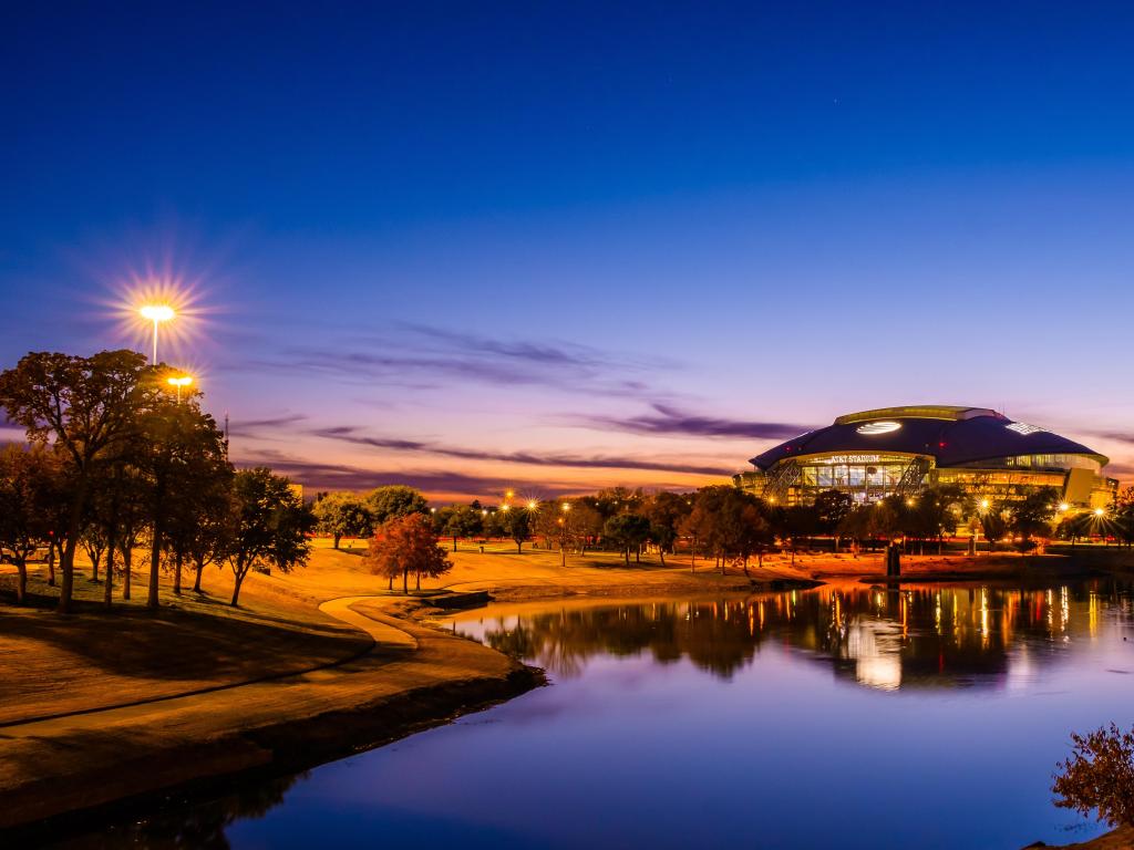 Arlington, Texas, USA with a view of the ATT football Stadium at night with a lake in the foreground. 