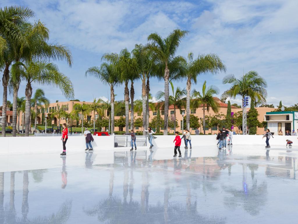 People ice skating in downtown San Diego in winter with palm trees in the background 