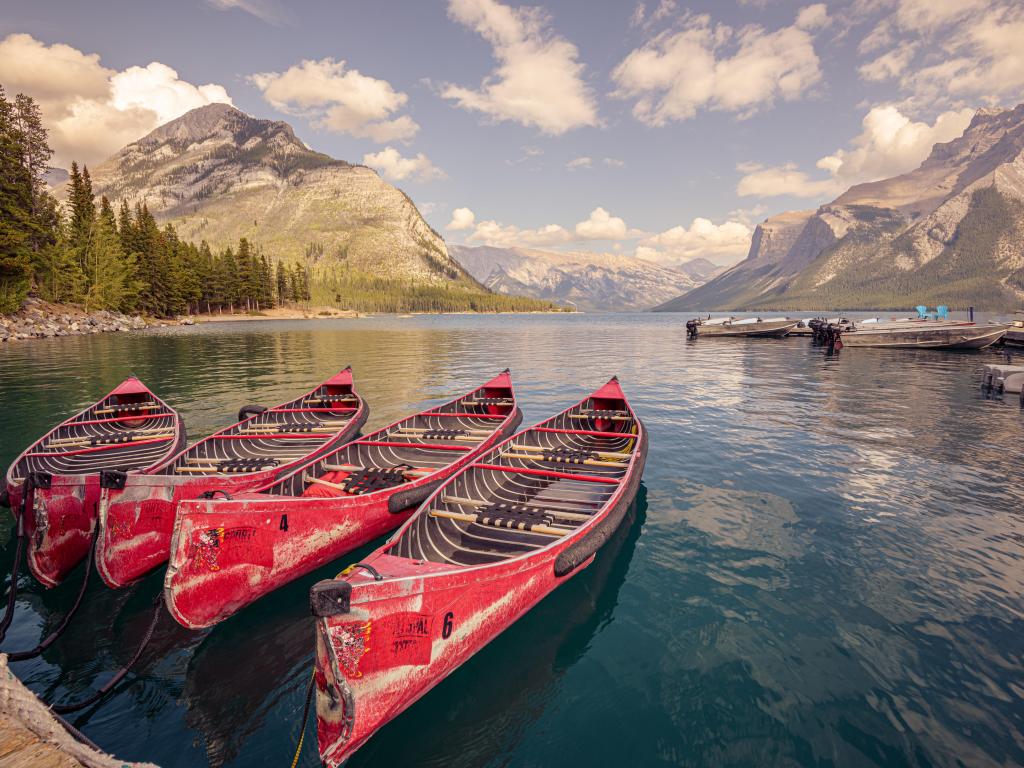 Striking red canoes lined up ready to take across the expansive Lake Minnewanka, Canada