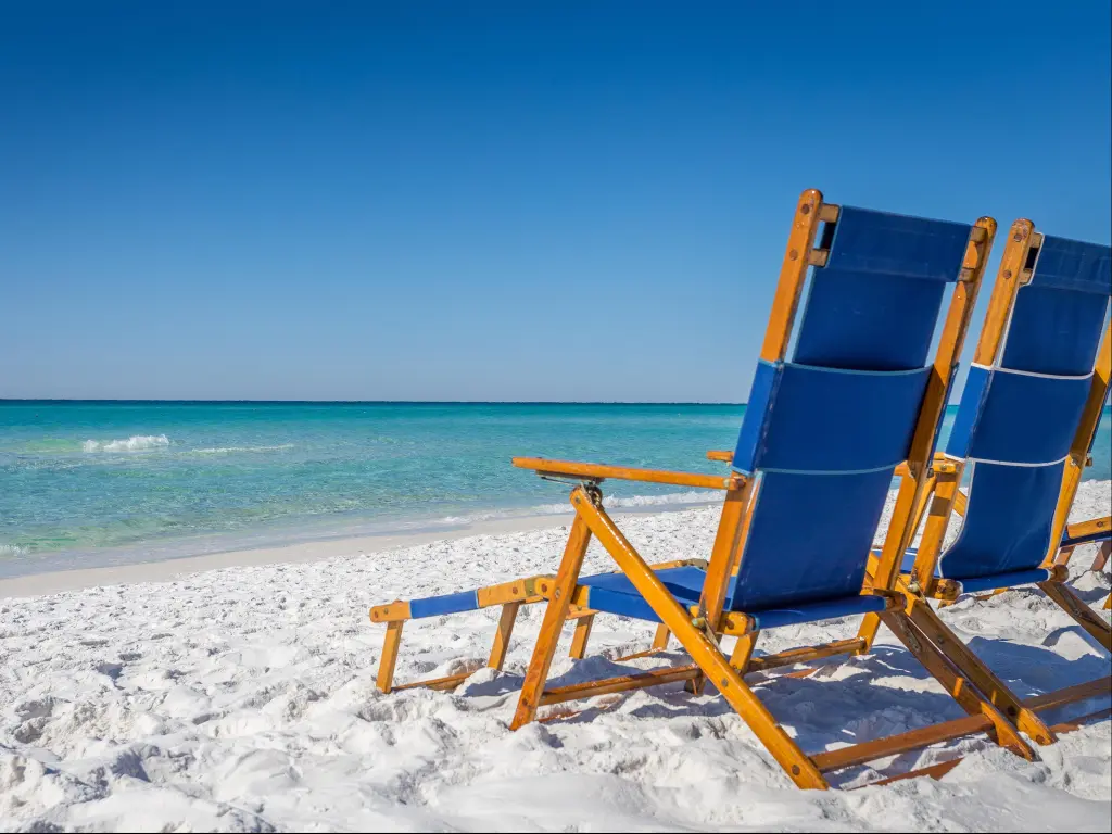 Two blue loungers on white sands, facing turquoise blue waters in Destin.