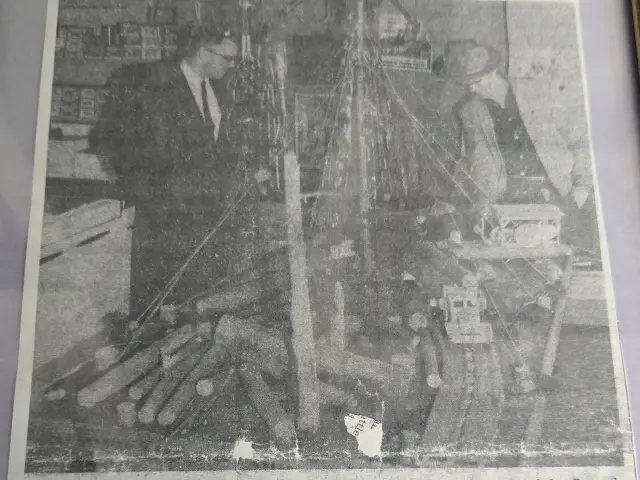 A black and white photo (newspaper cutting) depicting two men standing next to the diorama