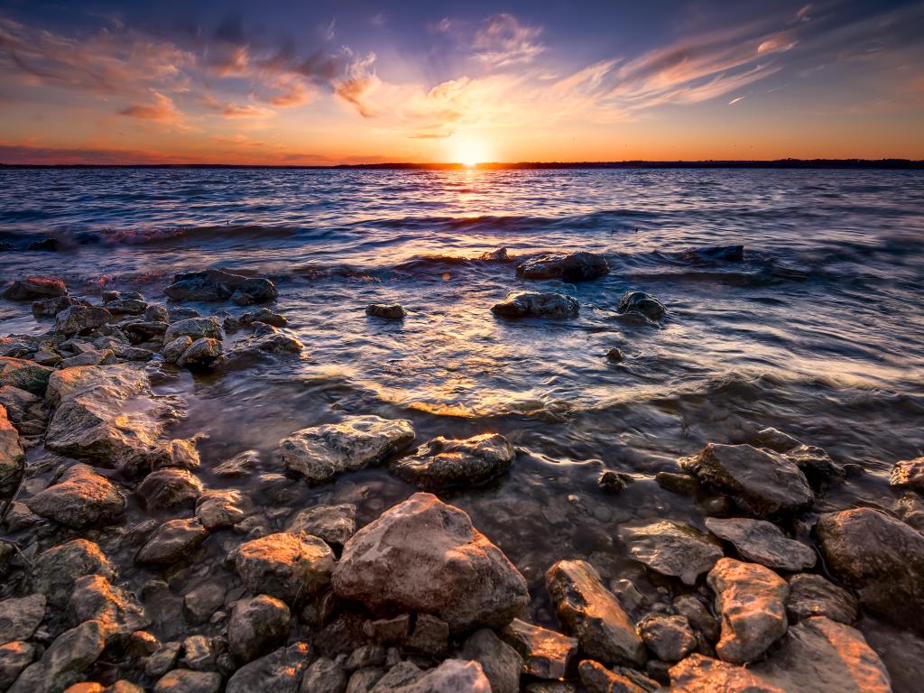 Colourful sunset over Benbrook Lake, Texas, with a rocky shoreline in the foreground