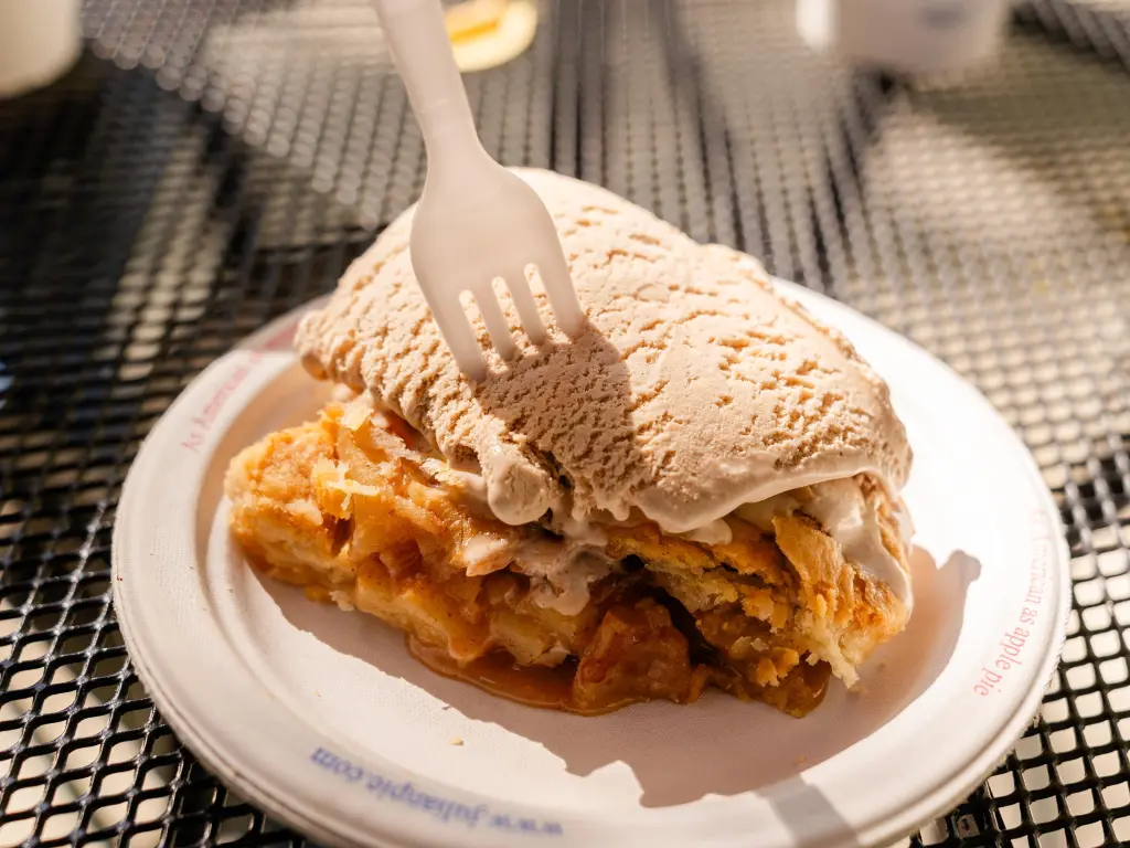 A plate of Julian's famous apple pie, with a scoop of ice cream and fork resting on top