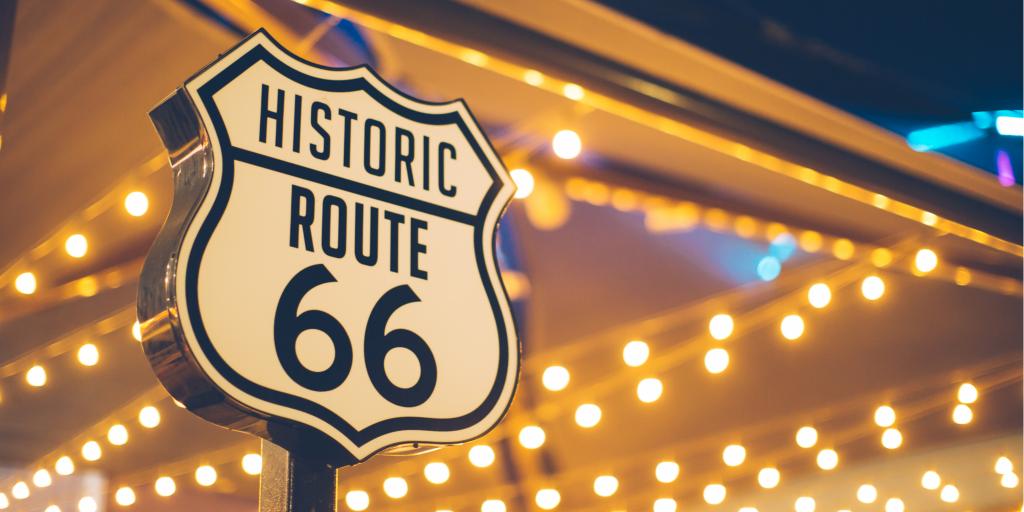 Route 66 road sign in front of fairy lights in the USA