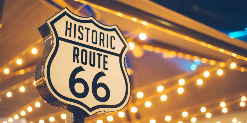 Route 66 road sign in front of fairy lights in the USA