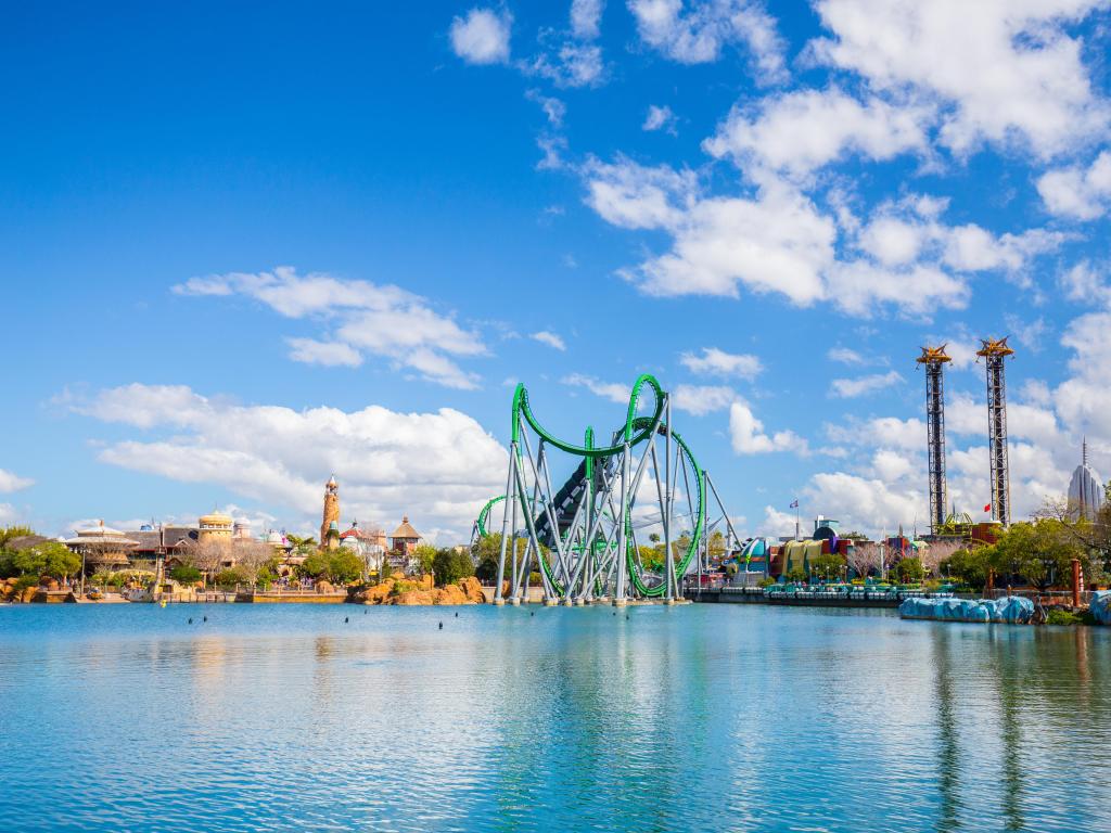 Walt Disney Orlando, USA with a large lake in the foreground and rides in the background on a sunny day with a blue sky above.