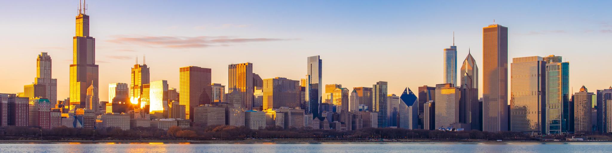 High rise buildings illuminated by bright sunset reflected in lake