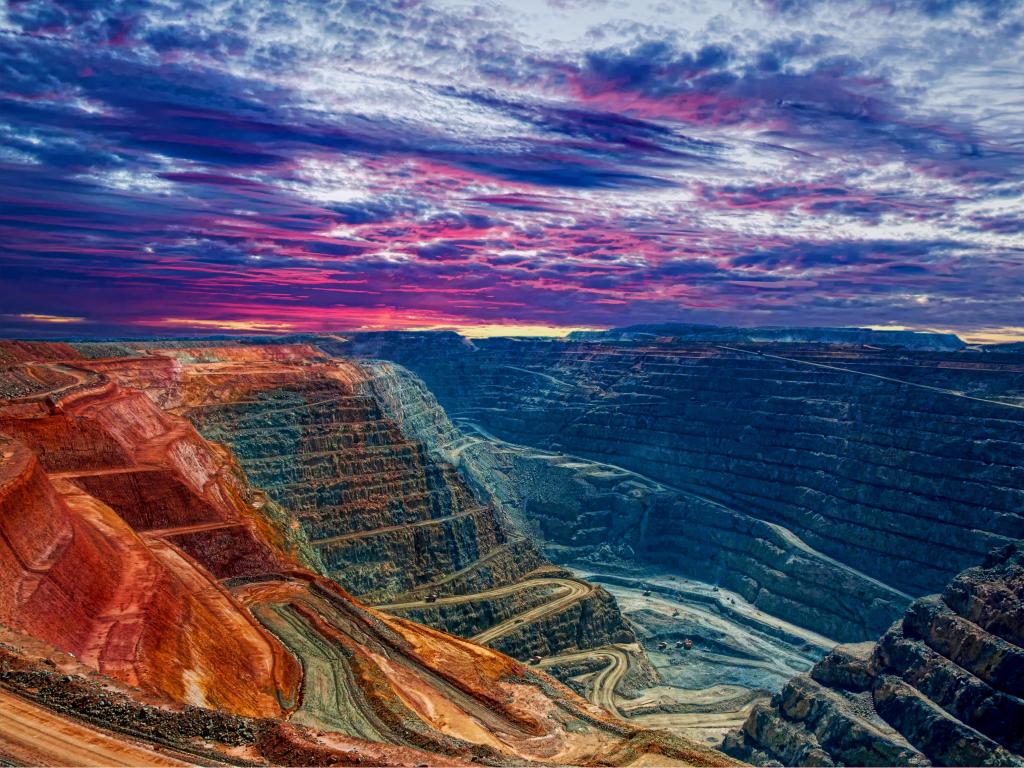 Kalgoorlie, Australia at sunset with purples and blues in the sky looking down on the canyons which are shades of orange, yellows and blue.