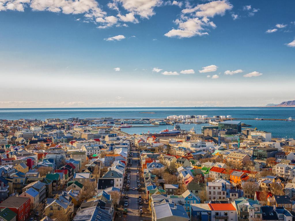 The capital city of Iceland, Reykjavik, seen from above on a clear sunny day, with colorful buildings lining the streets and the sea in the background