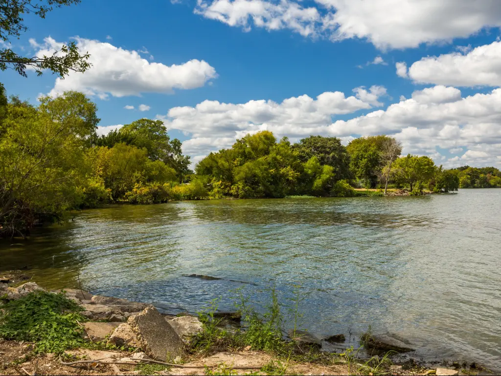 Lake Tawakoni, Texas, with lush trees surrounding and a rocky beach in the foreground