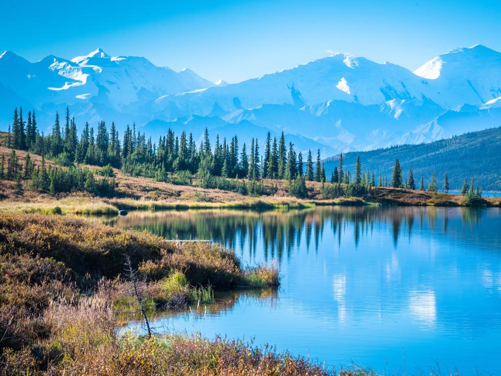 Wonder lake in Denali National Park, Alaska, with mountains in the background and a blue sky above