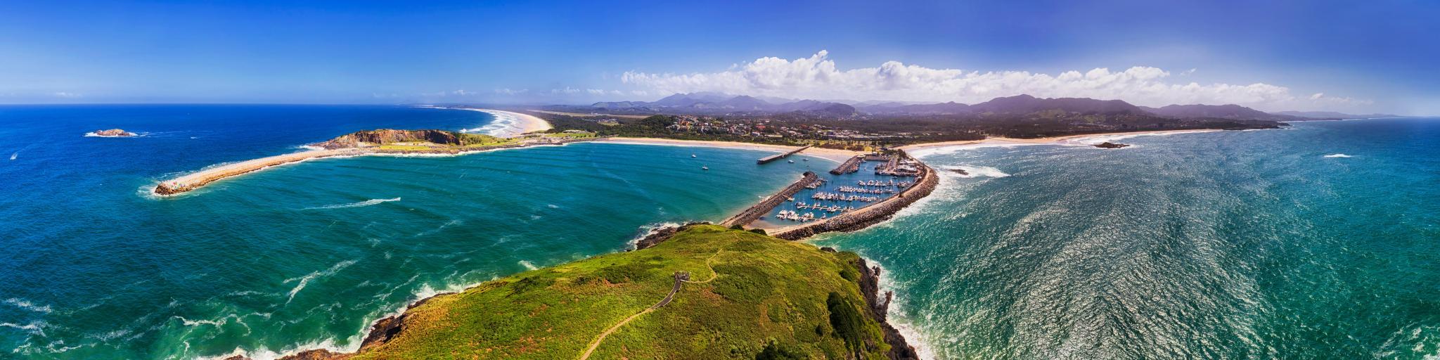 Aerial view of Coffs Harbour, NSW, Australia, showing vivid green land, blue sea and a sandy beach