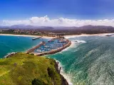 Aerial view of Coffs Harbour, NSW, Australia, showing vivid green land, blue sea and a sandy beach