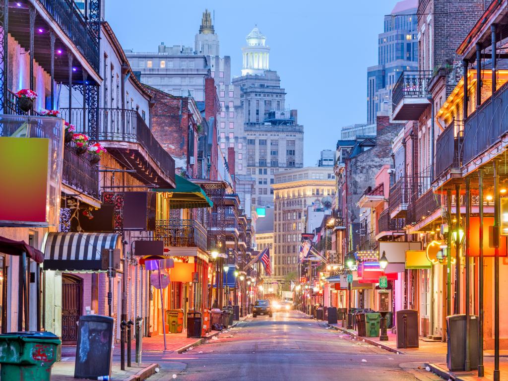 New Orleans, USA showing a busy street with bars and restaurants either side of the road at twilight, and tall buildings in the background.