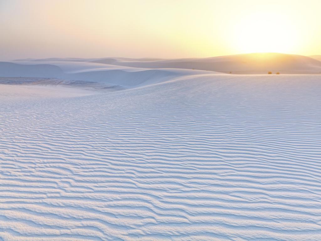 White Sands National Monument, New Mexico, USA with a dramatic sunset and white sand in the foreground.